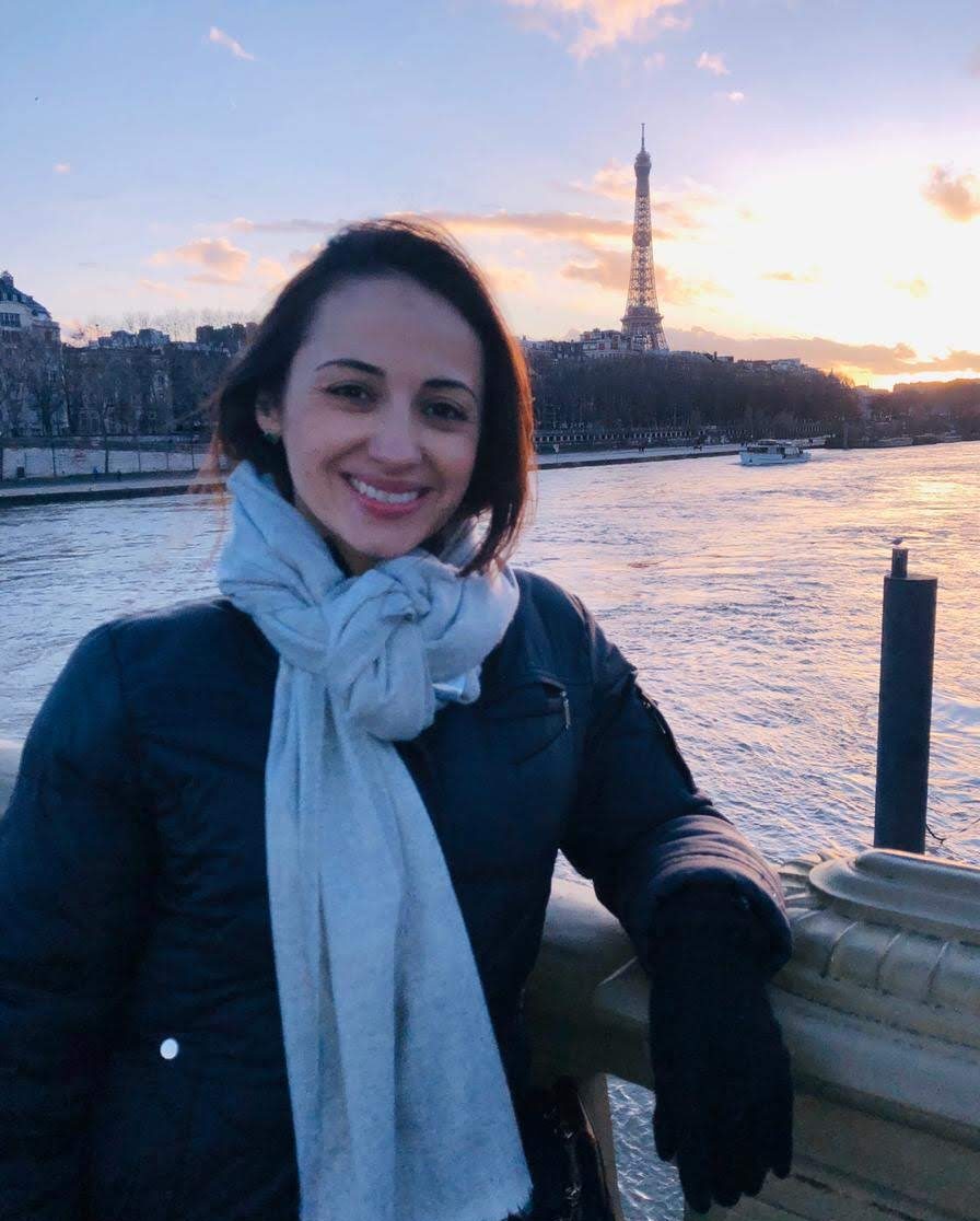 uma mulher na beira do rio sena com a torre eifel de fundo.